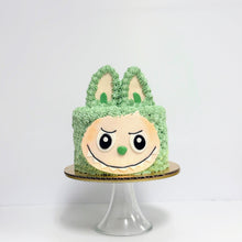Load image into Gallery viewer, Green cake with a face design on a white background